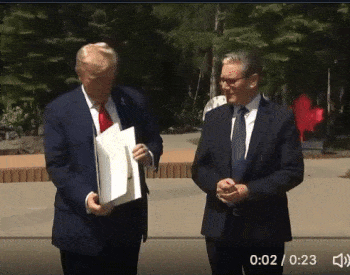 Donald Trump stands at a podium and drops a stack of trade deal documents onto the floor. The background suggests a formal press conference setting. Text reads Trump drops trade deal documents. The tone is dramatic and critical, highlighting carelessness or disregard for official paperwork.